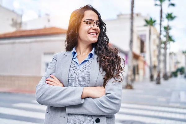 Young hispanic woman executive smiling confident standing with arms crossed gesture at street