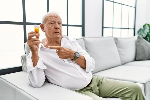 Senior Man Holding Pills Pointing Aside Worried Nervous Forefinger Concerned — Stock fotografie