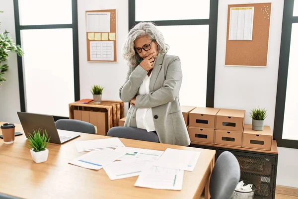 Ofiste çalışan orta yaşlı, kır saçlı bir iş kadını..