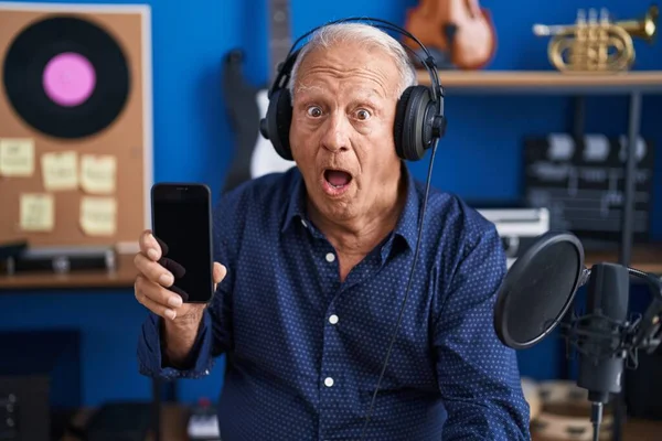Senior Man Grey Hair Showing Smartphone Screen Music Studio Scared — Zdjęcie stockowe