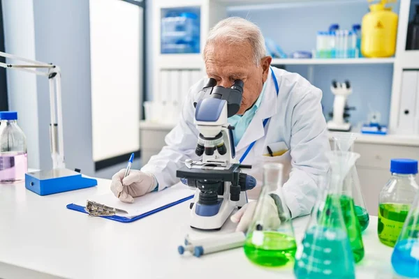 研究室で顕微鏡を使って科学者の制服を着た先輩 — ストック写真