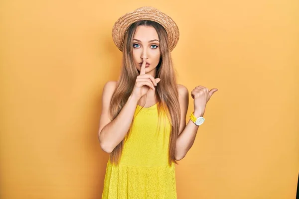 若いブロンドの女の子は夏の帽子をかぶって 唇に手で側に指して指で静かにするように求めている 沈黙と秘密の概念 — ストック写真