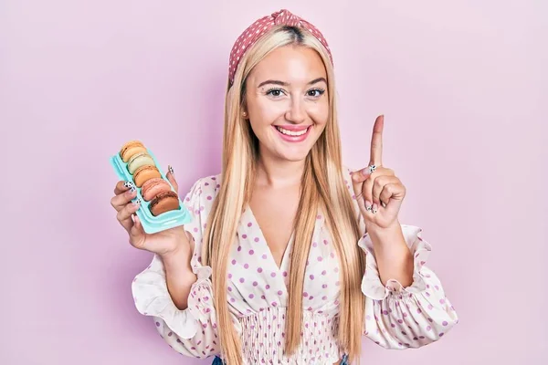 Menina Loira Jovem Segurando Deliciosos Macarons Doces Sorrindo Com Uma — Fotografia de Stock