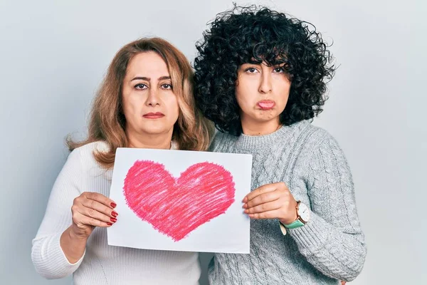 Middle east mother and daughter holding paper with heart draw depressed and worry for distress, crying angry and afraid. sad expression.