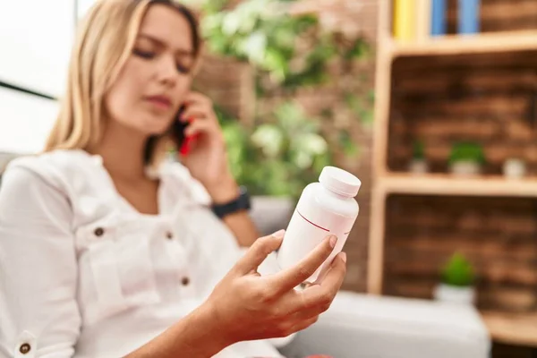 Mujer Hispana Joven Hablando Teléfono Inteligente Buscando Pastillas Botella Casa —  Fotos de Stock