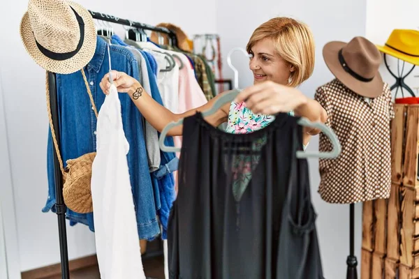 Middle age blonde woman smiling confident shopping at clothing store