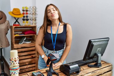 Genç esmer bir kadın perakende dükkanında açık mesajla afiş tutuyor kameraya bakıyor ve güzel ve seksi bir şekilde havadan öpücük yolluyor. aşk ifadesi. 