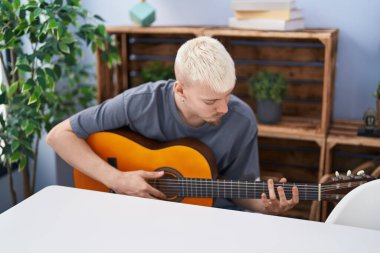 Young caucasian man playing classical guitar at home