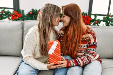 Evde Noel dekorunun yanında oturan hediye sahibi kadın çift şaşırdı.