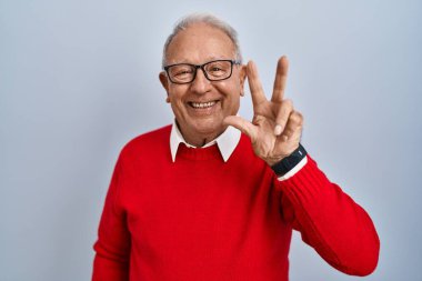Senior man with grey hair standing over isolated background showing and pointing up with fingers number three while smiling confident and happy. 
