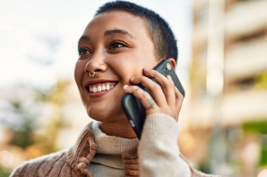 Kısa saçlı, gülümseyen, telefonda konuşan genç İspanyol kadın.