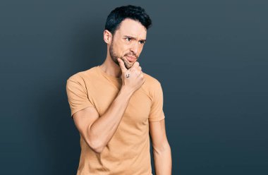 Sakallı, sıradan tişörtlü İspanyol bir adam bir soru hakkında endişeli ve gergin bir şekilde düşünüyor. 