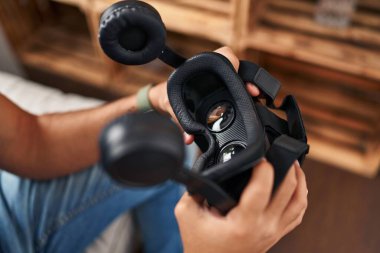 Genç İspanyol adam evde sanal gerçeklik gözlüğü tutuyor.