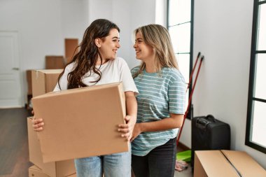 Genç ve güzel bir çift mutlu bir şekilde gülümsüyor. Yeni evlerinde karton kutu tutuyorlar..