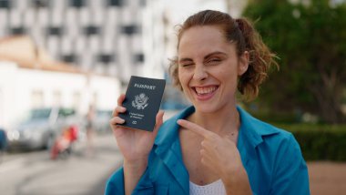 Young woman smiling confident holding united states passport at street