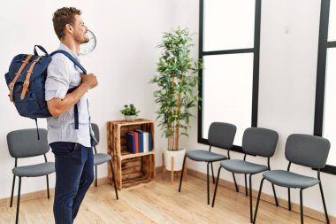 Sırt çantalı genç İspanyol adam bekleme odasında bekliyor.