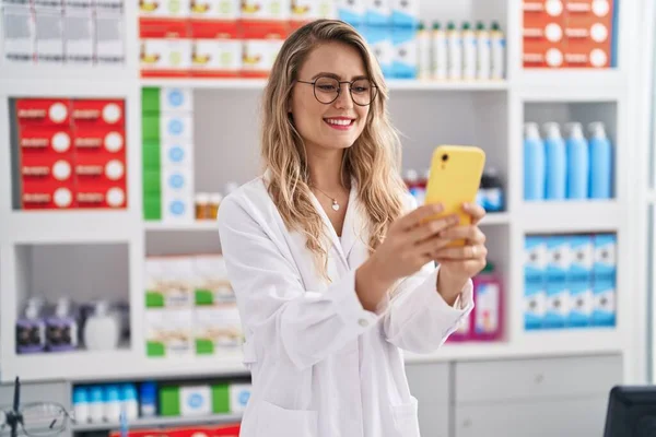 Young Woman Pharmacist Smiling Confident Using Smartphone Pharmacy — Zdjęcie stockowe