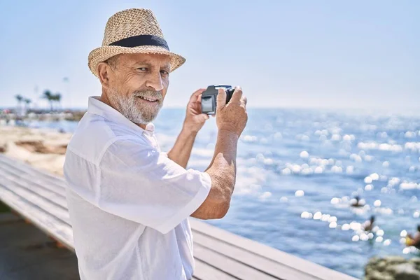 Uomo Anziano Sorridente Fiducioso Indossa Cappello Estivo Utilizzando Fotocamera Mare — Foto Stock