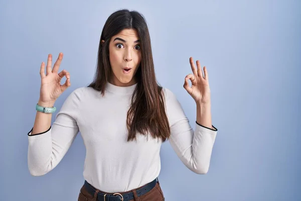 Mujer Morena Joven Pie Sobre Fondo Azul Mirando Sorprendido Sorprendido —  Fotos de Stock