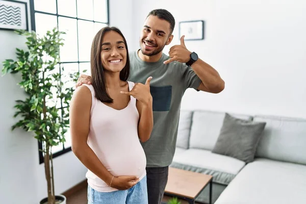 年轻的跨种族夫妇期待着孩子 触摸怀孕的腹部微笑着用手和手指做着电话手势 就像在电话里说话一样 交流概念 — 图库照片