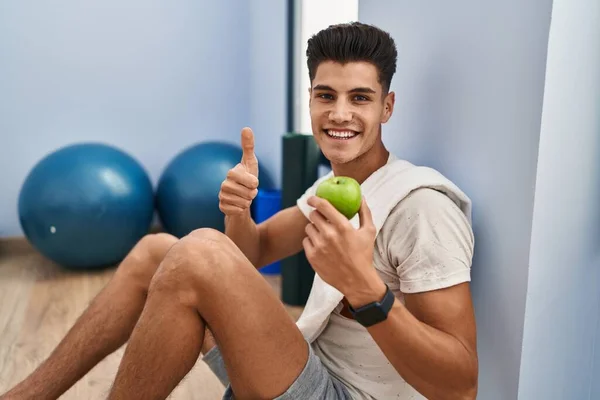 Young Hispanic Man Wearing Sportswear Eating Healthy Apple Smiling Happy — Fotografia de Stock