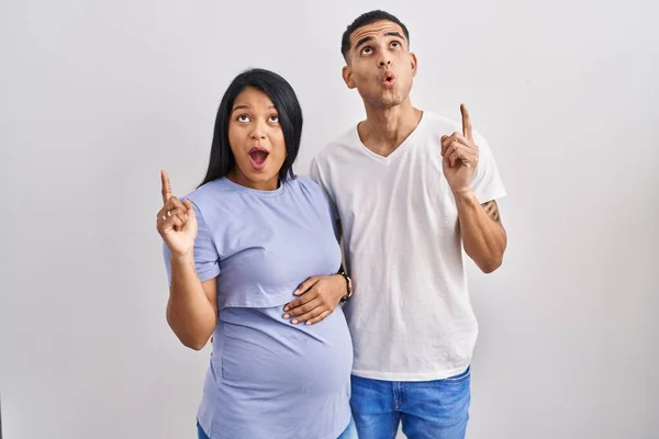 Jong Latino Paar Verwacht Een Baby Staan Achtergrond Verbaasd Verrast — Stockfoto