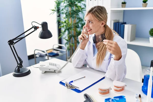 Young Blonde Woman Wearing Dentist Uniform Talking Telephone Holding Xray — Stockfoto