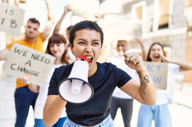 Bir grup genç aktivist ellerinde bayrak, ellerinde megafonla şehri protesto ediyorlar..