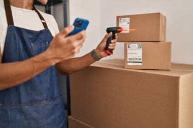 Young hispanic man ecommerce business worker scanning package at office