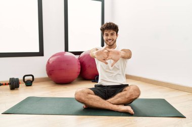 Genç İspanyol adam gülümsüyor spor merkezinde esniyor.