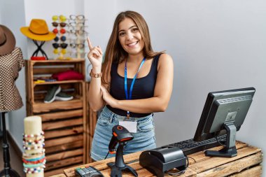 Perakende dükkanında açık mesajla pankart tutan genç esmer bir kadın yüzünde kocaman bir gülümsemeyle kameraya el ile işaret ediyor.. 