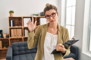 Muayenehanede çalışan genç bir kadın üzgün ve üzgün görünüyor, parmaklarıyla yön gösteriyor, mutsuz ve depresif.. 