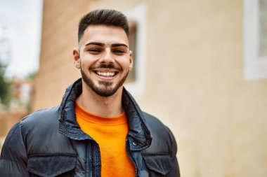 Yakışıklı, sakallı, neşeli ve kendine güvenen, kışlık palto giyen bir İspanyol.