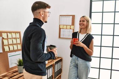 İki iş adamı gülümsüyor, ofiste kahve içiyorlar..