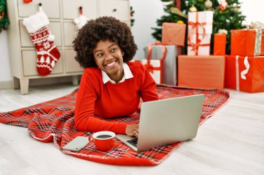 Genç Afro-Amerikalı kadın evde dizüstü bilgisayar kullanıyor.