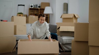 Orta yaşlı İspanyol kadın sokakta boks paketini açıyor.