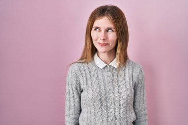 Pembe arka planda duran güzel bir kadın gülümseyip yan tarafa bakıyor ve düşünüyor.. 