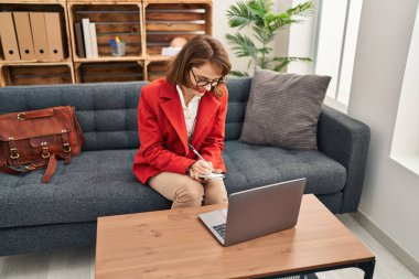 Beyaz kadın psikolog psikoloji merkezinde online danışmanlık yapıyor.