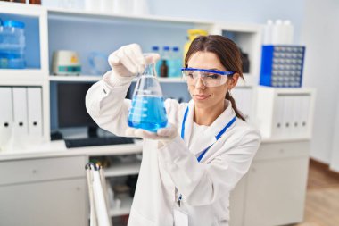 Laboratuvarda deney tüpü tutan bilim adamı üniforması giyen İspanyol genç bir kadın.