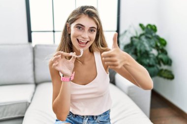 Görünmez hizada duran genç sarışın kadın elle olumlu jest yapıyor, gülümsüyor ve başarı için seviniyor. kazanan jest. 