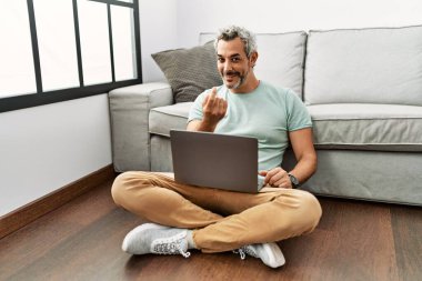 Orta yaşlı, İspanyol bir adam oturma odasında dizüstü bilgisayar kullanıyor. Bizi çağırıyor. El hareketleriyle, mutlu bir şekilde karşılamaya ve gülümsemeye davet ediyor. 