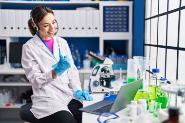 Hispanic woman working at scientist laboratory smiling happy and positive, thumb up doing excellent and approval sign 