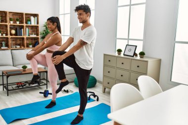 Genç Latin sporcu çift gülümseyerek evde mutlu bir antrenman yapıyor..