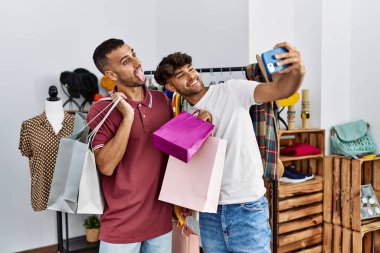 İki İspanyol müşteri alışveriş torbaları tutuyor ve giyim mağazasındaki akıllı telefonun yanında selfie çekiyor..