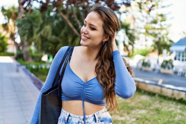 Genç İspanyol kız gülümseyerek şehirde mutlu mesut dikiliyor..