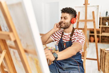 Sanat stüdyosunda müzik dinleyen genç bir Arap sanatçı..