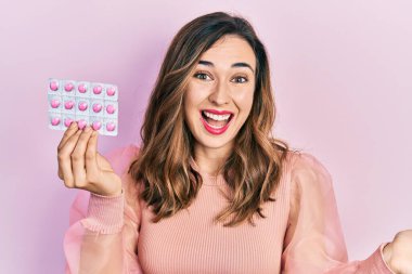 Genç İspanyol kız elinde haplarla başarıyı mutlu bir gülümsemeyle kutluyor ve kazanan el kaldırarak ifade ediyor. 