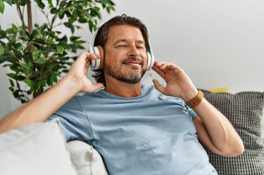 Middle age caucasian man smiling confident listening to music at home