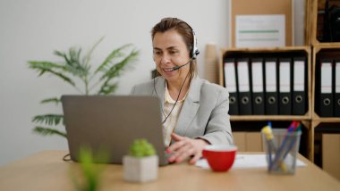 Orta yaşlı İspanyol kadın telefon merkezi ajanının ofiste görüntülü görüşmesi var.