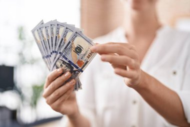 Ofiste dolarları tutan genç sarışın iş kadını.